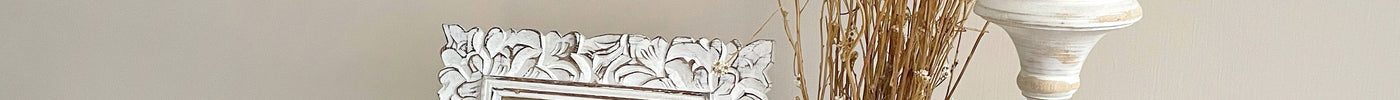White Wood Photo Frame and Candle Stick Holder with White Porcelain Vase with Flowers on a White Marble Table and Picture Frame in background