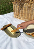 Hand Cutting Butter with Wooden Butter Knife and Green Stones Plates with Picnic Basket against green grass and white picnic blanket.