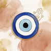 A classic blue and light-blue evil eye amulet centered against a soft watercolor background in warm terracotta and gold tones, accented with delicate line drawings of a Hamsa hand, olive sprigs, and traditional geometric motifs.