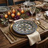 An elegantly set rustic wooden dinner table featuring Mediterranean-style hand-painted ceramic plates with blue, green, and gold medallion patterns.