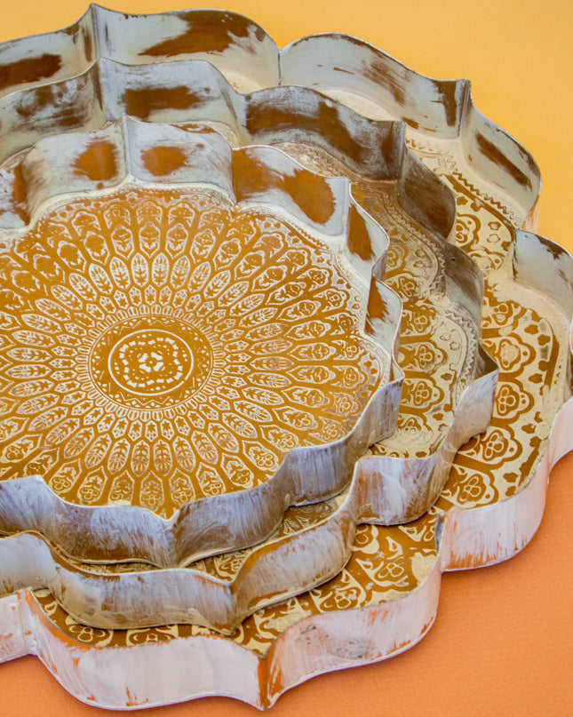 Decorative metal trays with intricate gold patterns on a yellow background