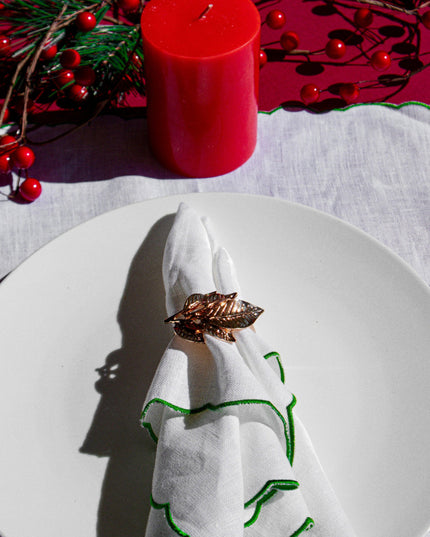 Gold Leaf Napkin Ring on a White Green Napkin Against a Decorative Holiday Background