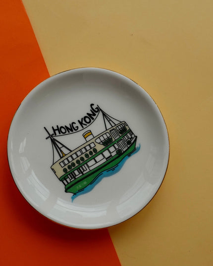 Small white dish with a drawing of a ferry and 'Hong Kong' text on an orange and beige background