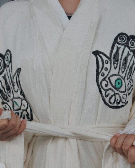 Person Wearing An Off-White Robe With Black Hand Designs And Green Evil Eyes