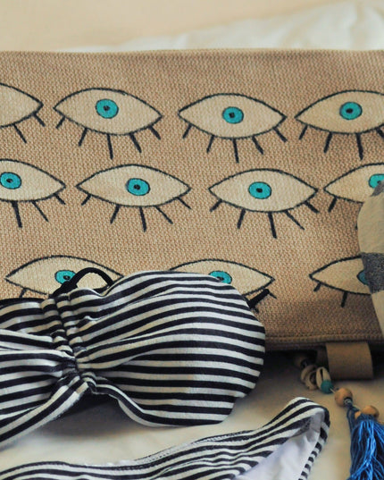 Striped bikini set with hand-painted evil eye beach bag on a light background