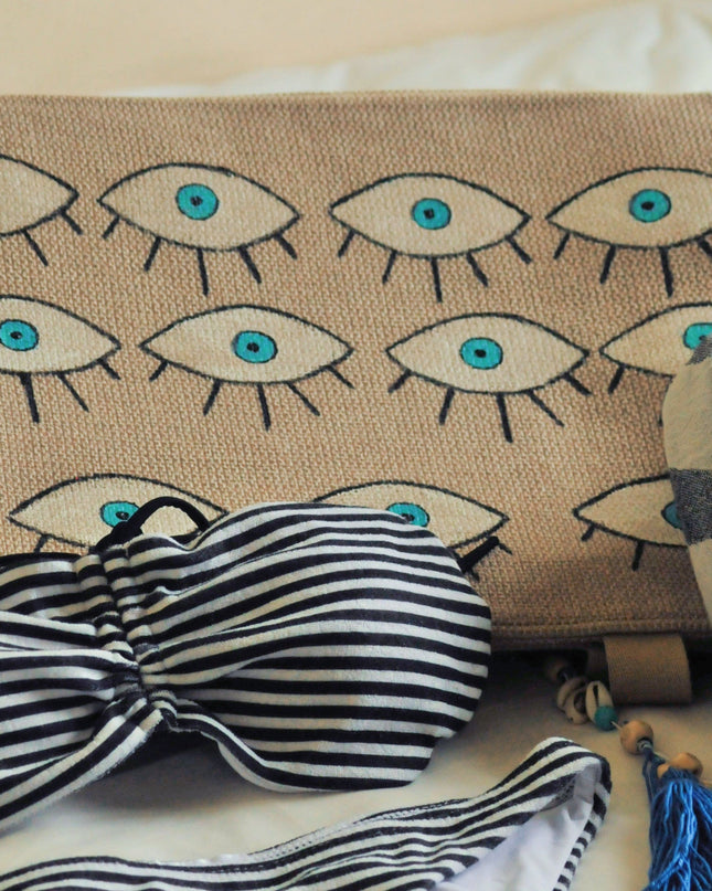 Striped bikini set with hand-painted evil eye beach bag on a light background