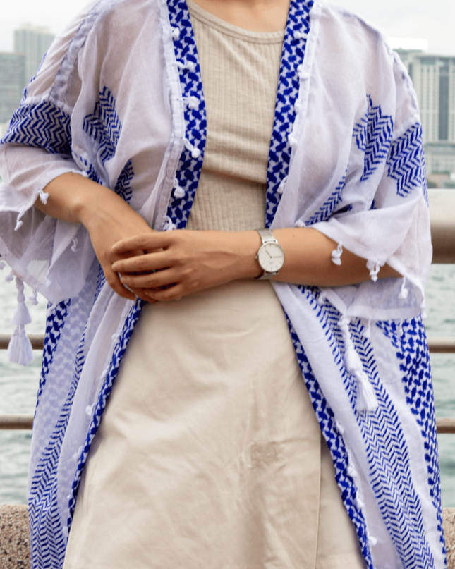Person wearing a blue and white patterned kimono-style garment with a cityscape background.