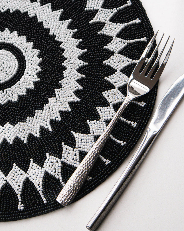 Black and white patterned placemat with a fork and knife on a white surface