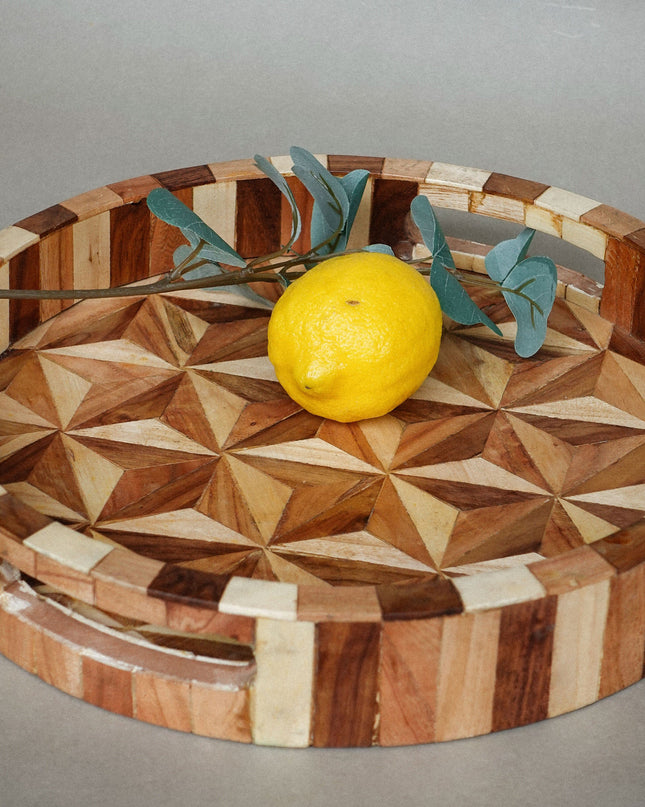 Wooden tray with geometric pattern and lemon on a gray background
