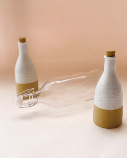 Two Beige Ceramic Bottles With Cork And A Glass Bottle