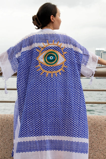 Casa Duniya's Hand-Painted Evil Eye Blue and White Beach Cover Up with Hong Kong Sklyline in the Background
