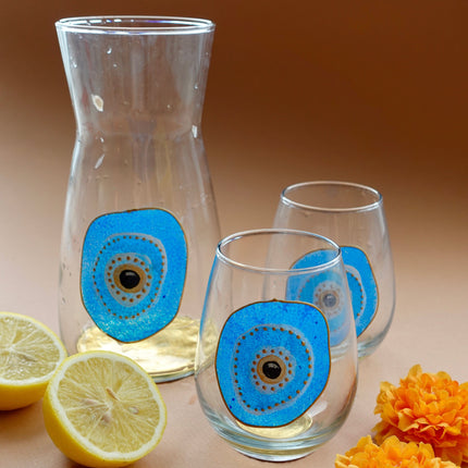 Hand-Painted Evil Eye Water Glasses and Carafe with flowers and lemons accents on a brown background