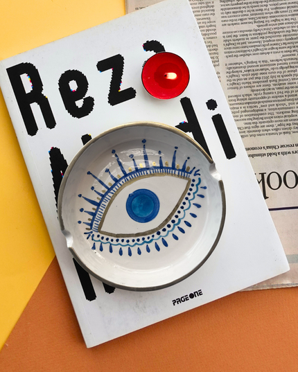 Decorative hand-painted evil eye ashtray on a magazine