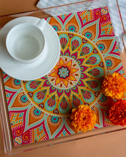 Colorful mandala-patterned tray with a white cup and saucer on a brown surface.