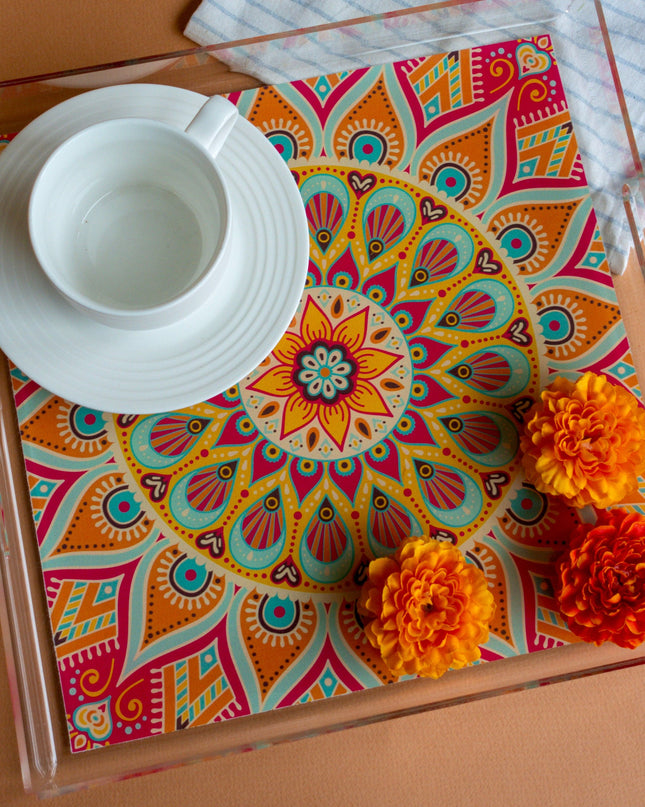 Colorful mandala-patterned tray with a white cup and saucer on a brown surface.