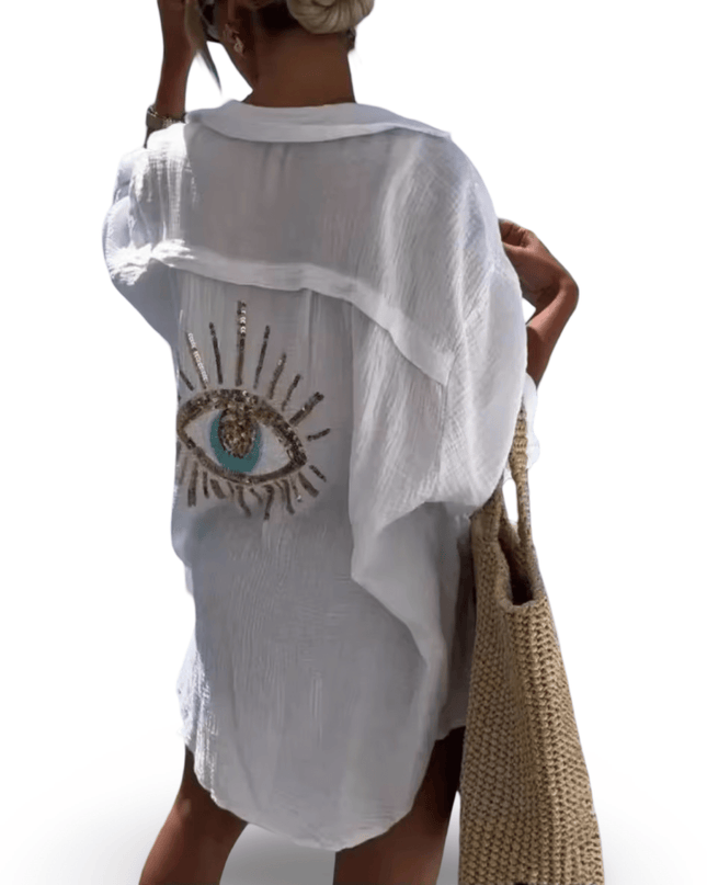 White sheer shirt with eye design worn by a person, holding a woven beach bag.