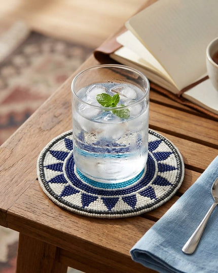 Nazar Geometric Beaded Coaster under a glass of water on a wooden table
