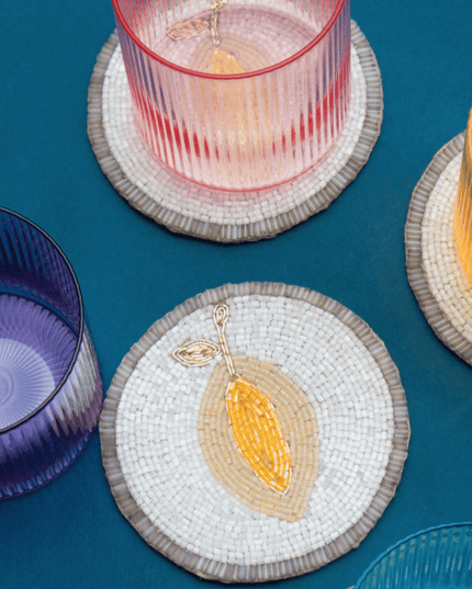 Colorful glassware on lemon beaded coasters against a blue background