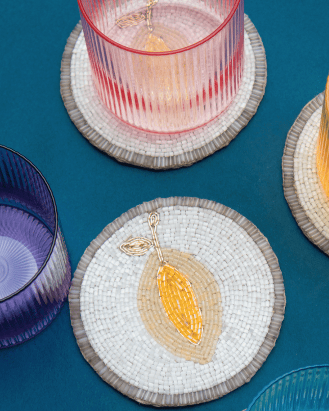 Colorful glassware on lemon beaded coasters against a blue background