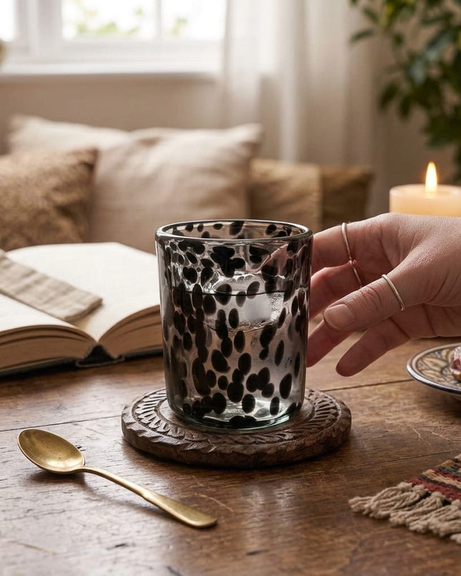 Casa Duniya Hand-Blown Black Water Glass on a Wooden Table Being Reached For Giulia Water Glass