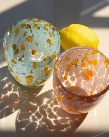 Two blown glass water glasswith floral patterns on a light surface