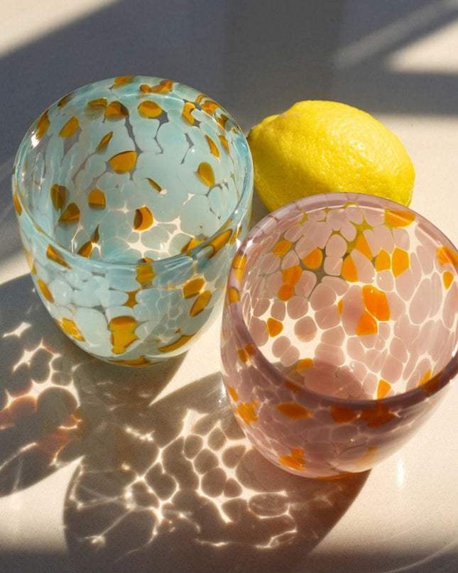 Two blown glass water glasswith floral patterns on a light surface