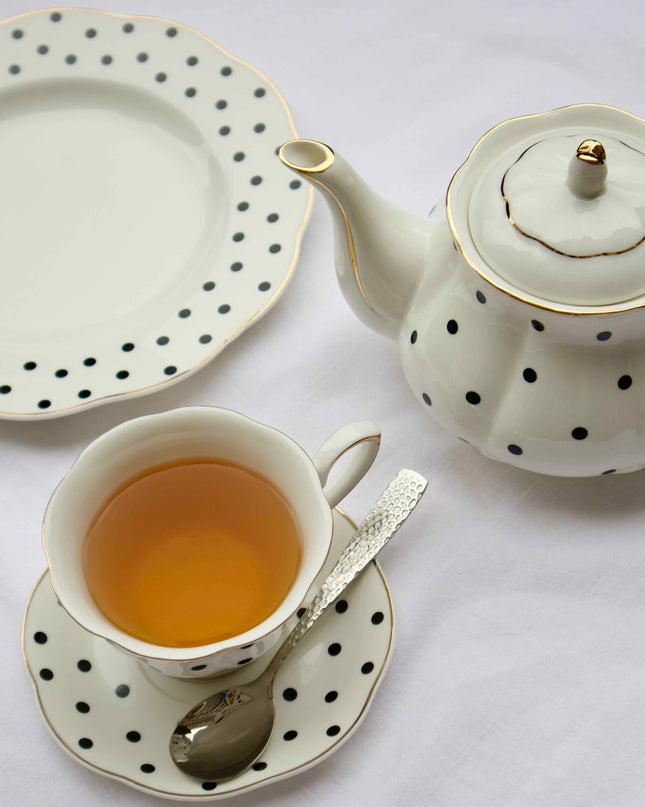 Polka Dot tea set with a teapot, cup, and saucer on a white tablecloth.