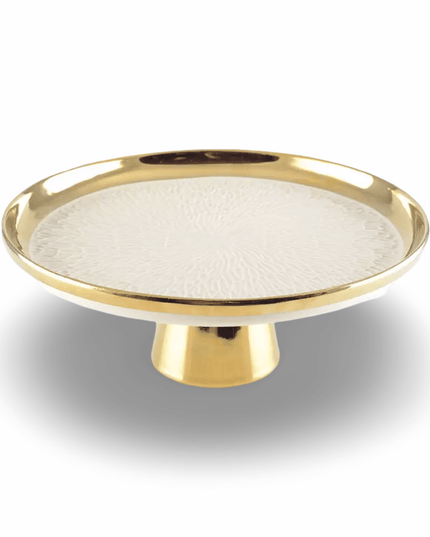 Decorative cake plate with gold rim on a pedestal and textured white center on a white background
