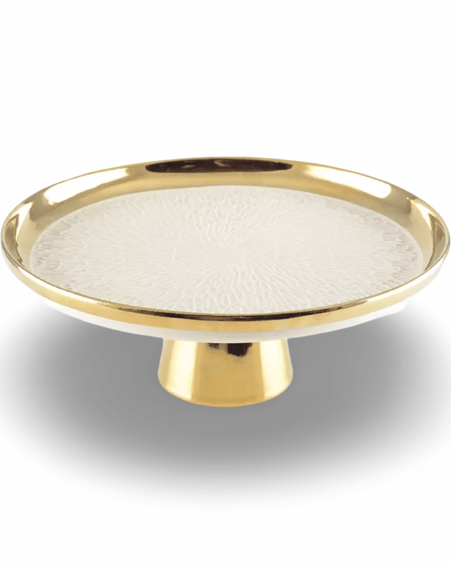 Decorative cake plate with gold rim on a pedestal and textured white center on a white background