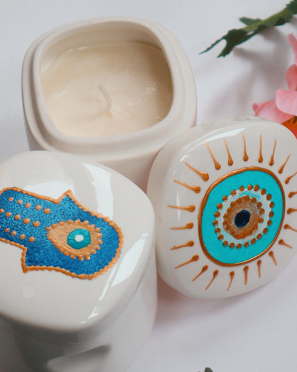 Decorative ceramic candle holders with hand-painted Hamsa hand and eye designs on a light background.