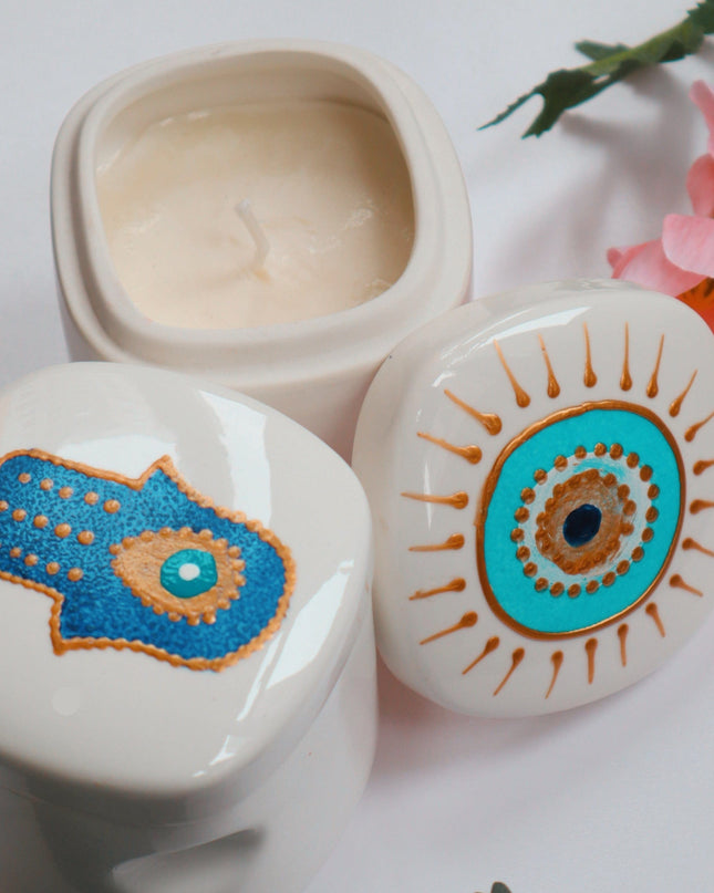 Decorative ceramic candle holders with hand-painted Hamsa hand and eye designs on a light background.