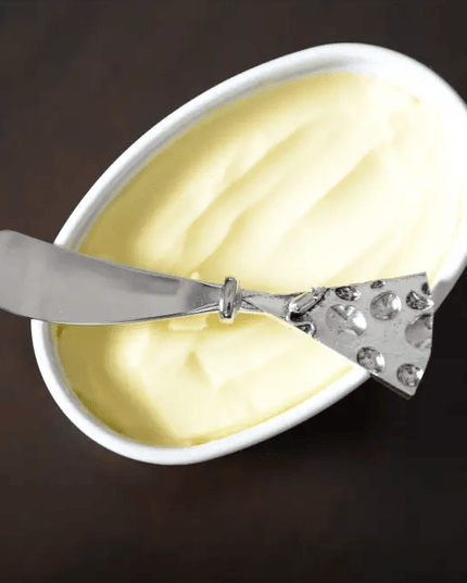 Hammered Silver Cheese Spreader on a Bowl with Cream cheese and a brown background