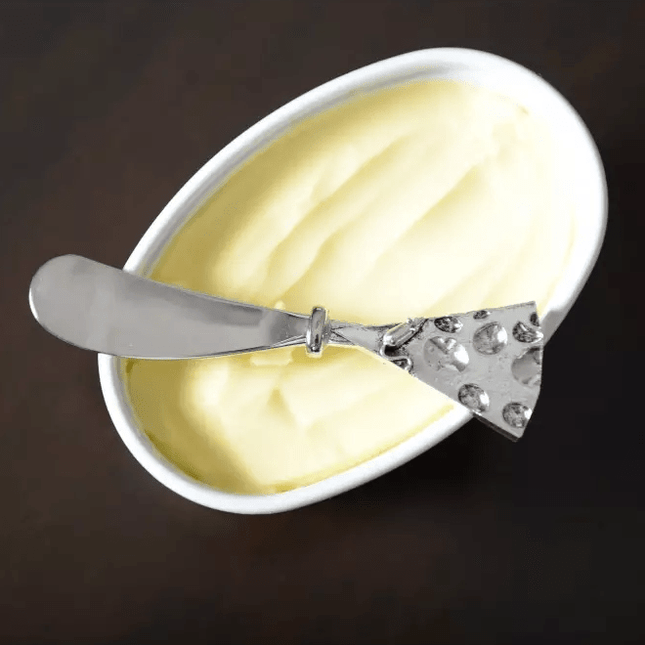 Hammered Silver Cheese Spreader on a Bowl with Cream cheese and a brown background
