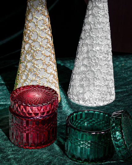 Decorative Christmas trees with red and green candle holders on a dark surface