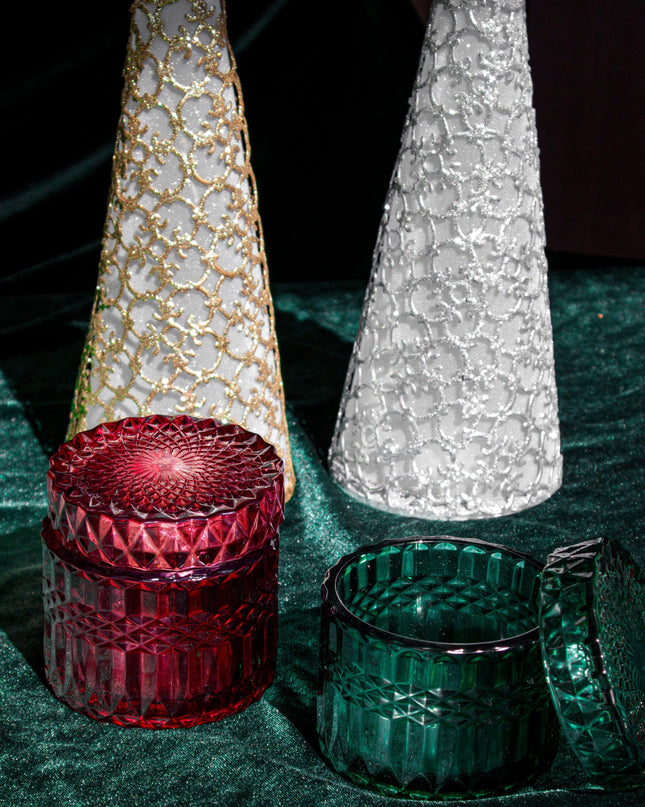 Decorative Christmas trees with red and green candle holders on a dark surface