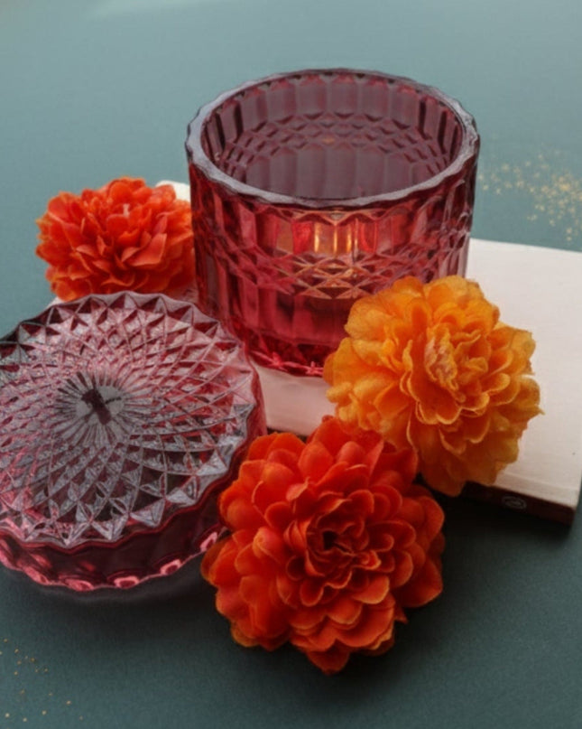 Decorative setup with red glass containers, orange flowers, and small candles on a teal surface.