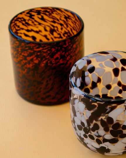 Two blown glass tumblers with leopard print pattern on a beige background