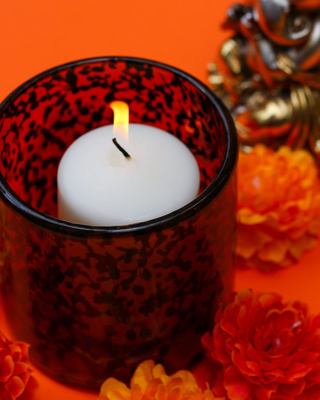 Brown blown glass Candle holder with flowers and a small statue of Ganesh on an orange background