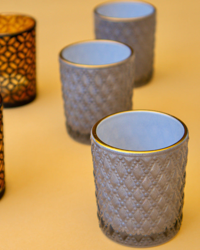 Set of textured glass candle holders on a beige surface