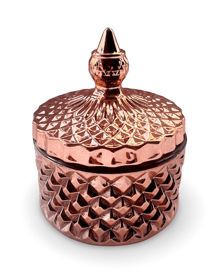 Decorative rose gold glass jar with a prism-cut design and a small finial on a white background