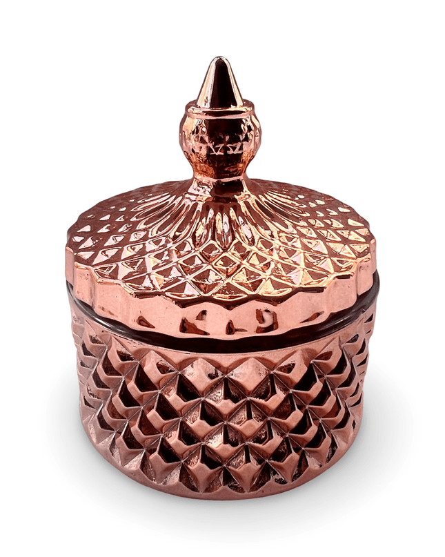 Decorative rose gold glass jar with a prism-cut design and a small finial on a white background