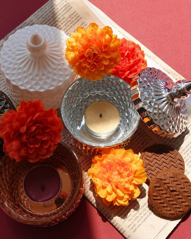 Decorative candles and flowers on a textured surface with a red background