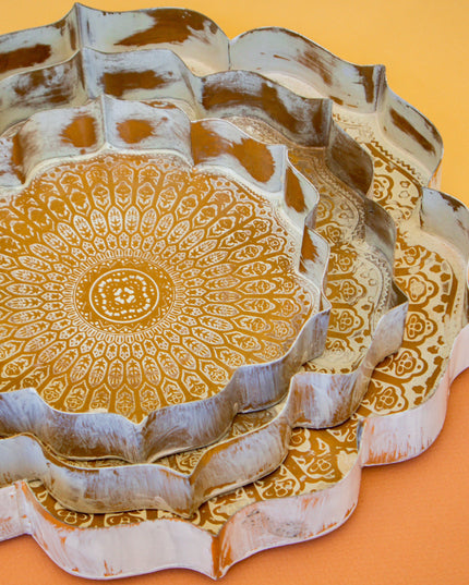Decorative metal trays with intricate gold patterns on a yellow background
