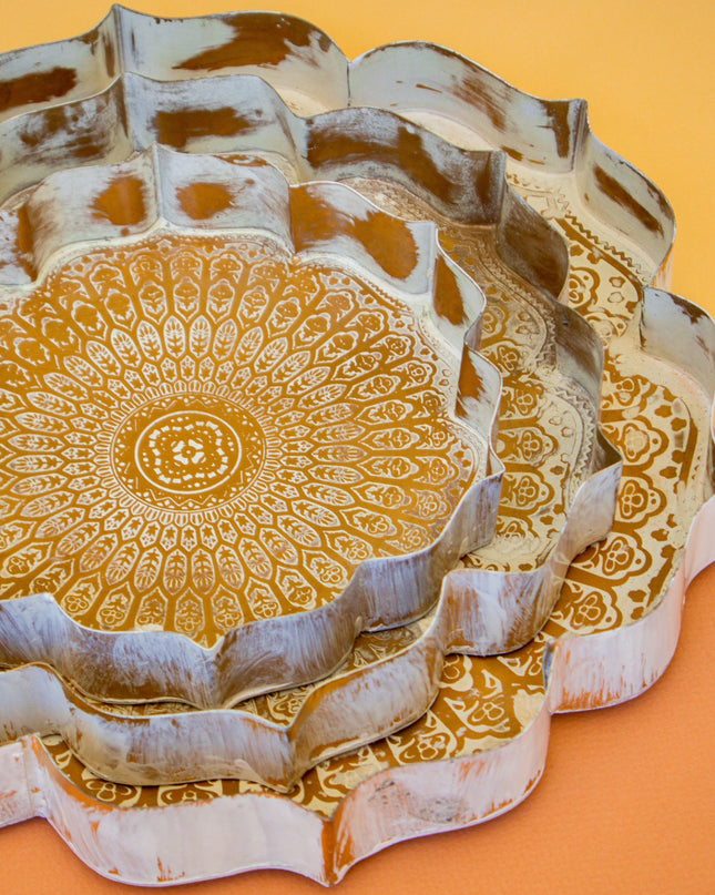 Decorative metal trays with intricate gold patterns on a yellow background
