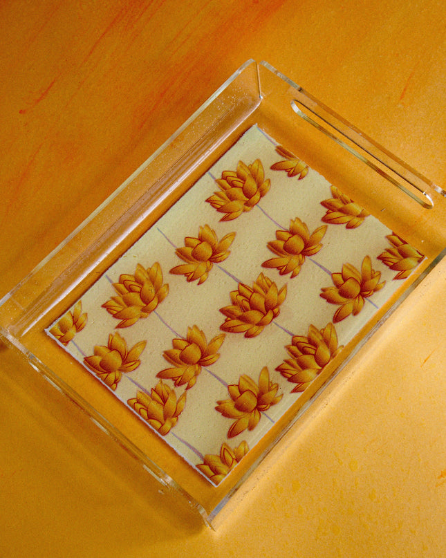 Clear acrylic tray with gold lotus design on a yellow surface