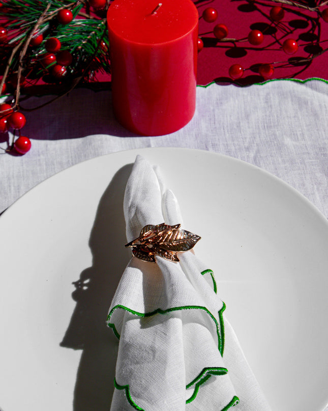 Gold Leaf Napkin Ring on a White Green Napkin Against a Decorative Holiday Background