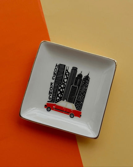 Square ceramic dish with Hong Kong cityscape design and Iconic Red Taxi on an orange and beige background