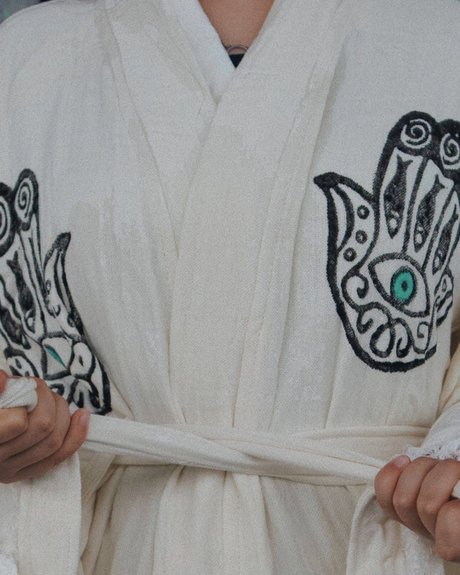 Person Wearing An Off-White Robe With Black Hand Designs And Green Evil Eyes