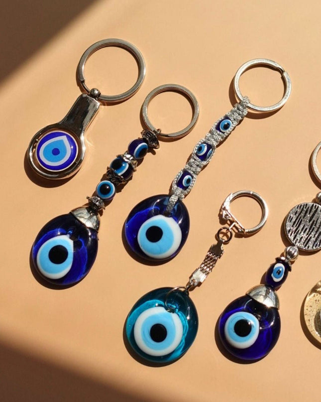 Set of keychains with blue evil eye designs on a beige surface