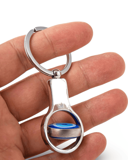 Silver keychain with a blue evil eye movable accent held in a hand against a white background